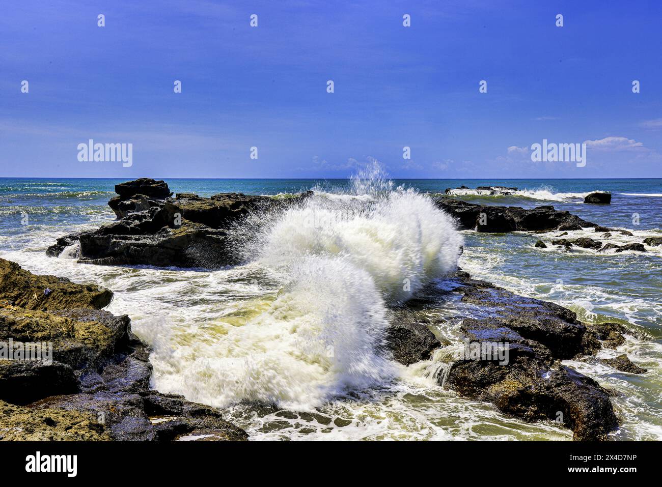 Onde che si infrangono sulle isole di roccia vulcanica lungo la costa meridionale di Bali, Indonesia Foto Stock
