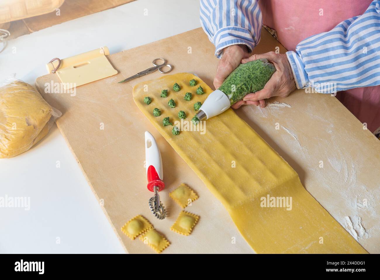 Pasta tradizionale italiana. Fase di preparazione dei ravioli con spinaci e ricotta utilizzando un sacchetto di pasta. Spinaci cotti e sminuzzati su pasta fatta in casa Foto Stock