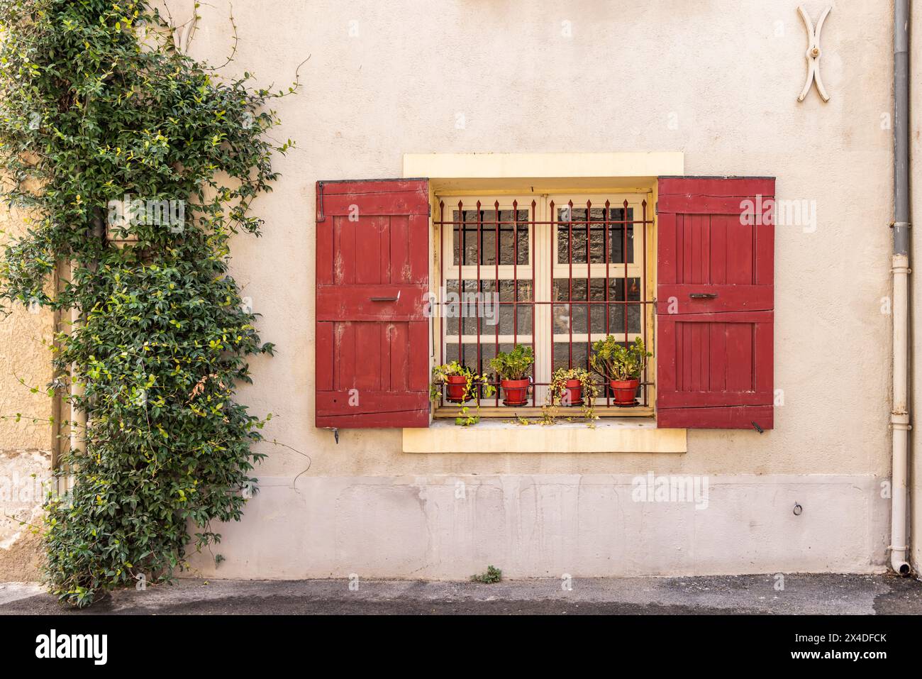 Aigues-Mortes, Gard, Occitania, Francia. Persiane rosse su una finestra sbarrata nel sud della Francia. Foto Stock