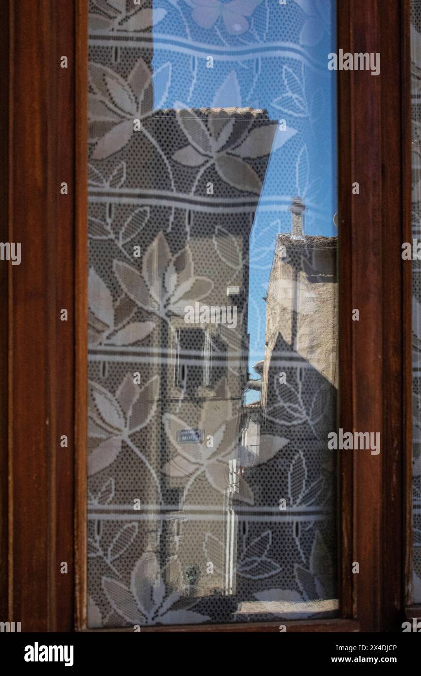 Antichi edifici di Viviers, Francia. Riflesso in una finestra con tendine. Foto Stock