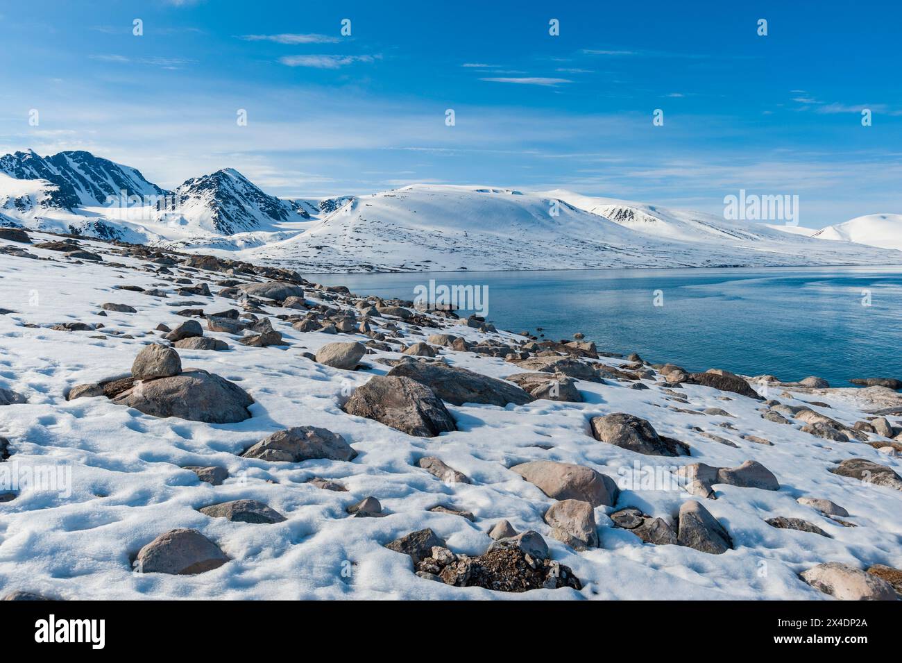 Spiagge rocciose innevate e montagne costeggiano Bockfjorden, Spitsbergen Island, Svalbard, Norvegia. Foto Stock