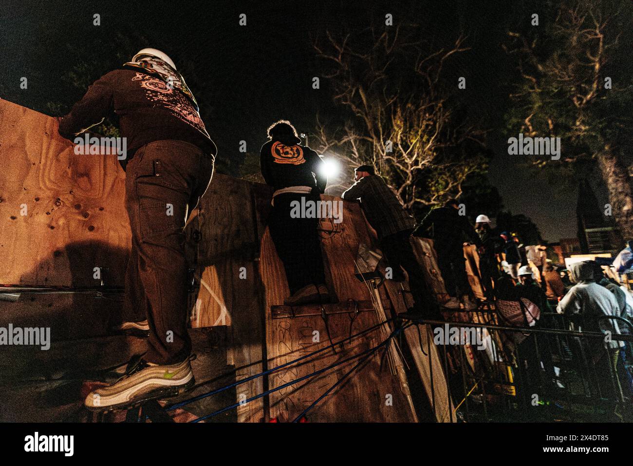 I manifestanti pro-palestinesi osservano le forze di polizia dell'area dall'accampamento costruito di fronte alla Royce Hall presso l'UCLA. Foto Stock