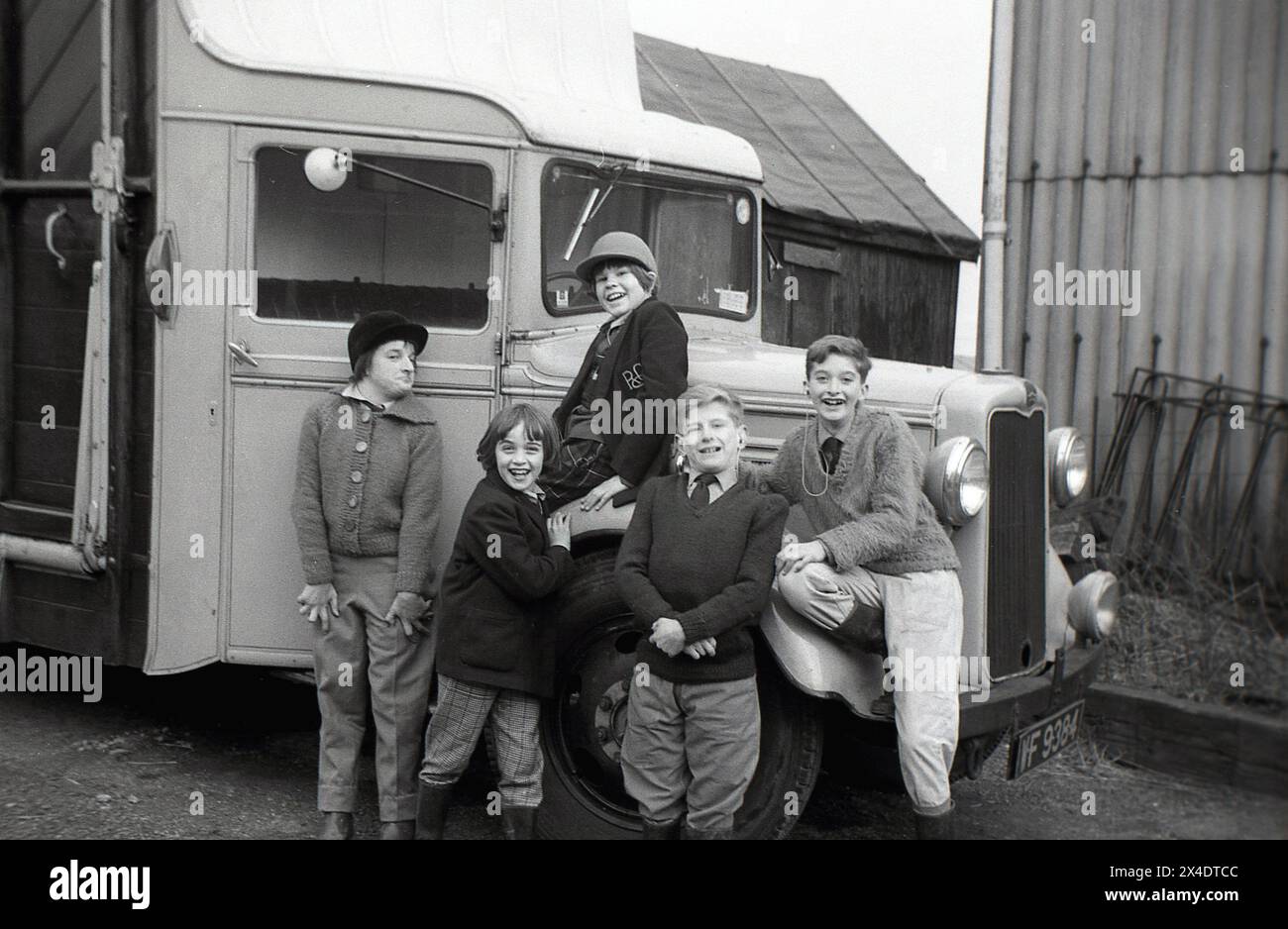 Anni '1960, bambini storici, scolari che si divertono sulla ruota del box o del furgone dell'epoca, in posa per una foto fuori nel cortile di una scuola di equitazione suburbana, Inghilterra, Regno Unito. Foto Stock