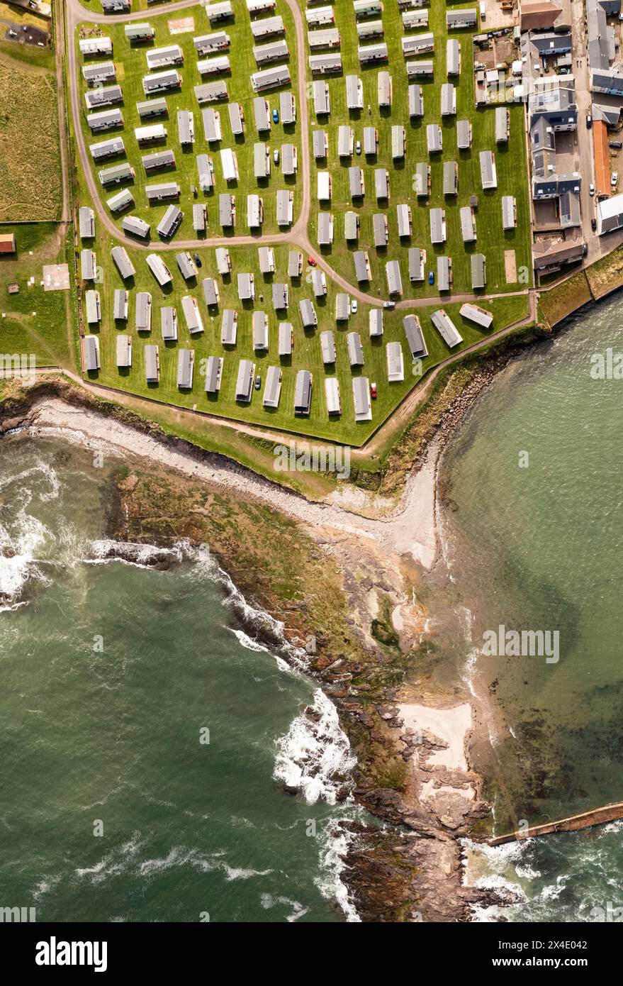 Vista aerea dall'alto verso il basso di un grande gruppo di roulotte statiche su un parcheggio per roulotte o una casa vacanze sulla costa in una località balneare per vacanze in famiglia Foto Stock