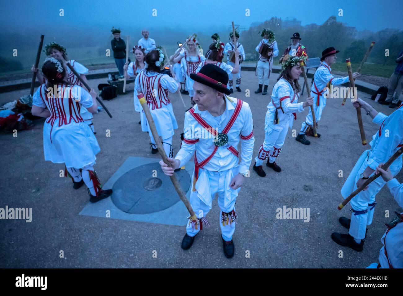 Le Belles of London City, gruppo femminile di Morris, si esibiscono in una danza del giorno di maggio durante un'alba nebbiosa a Primrose Hill, Londra, Regno Unito Foto Stock