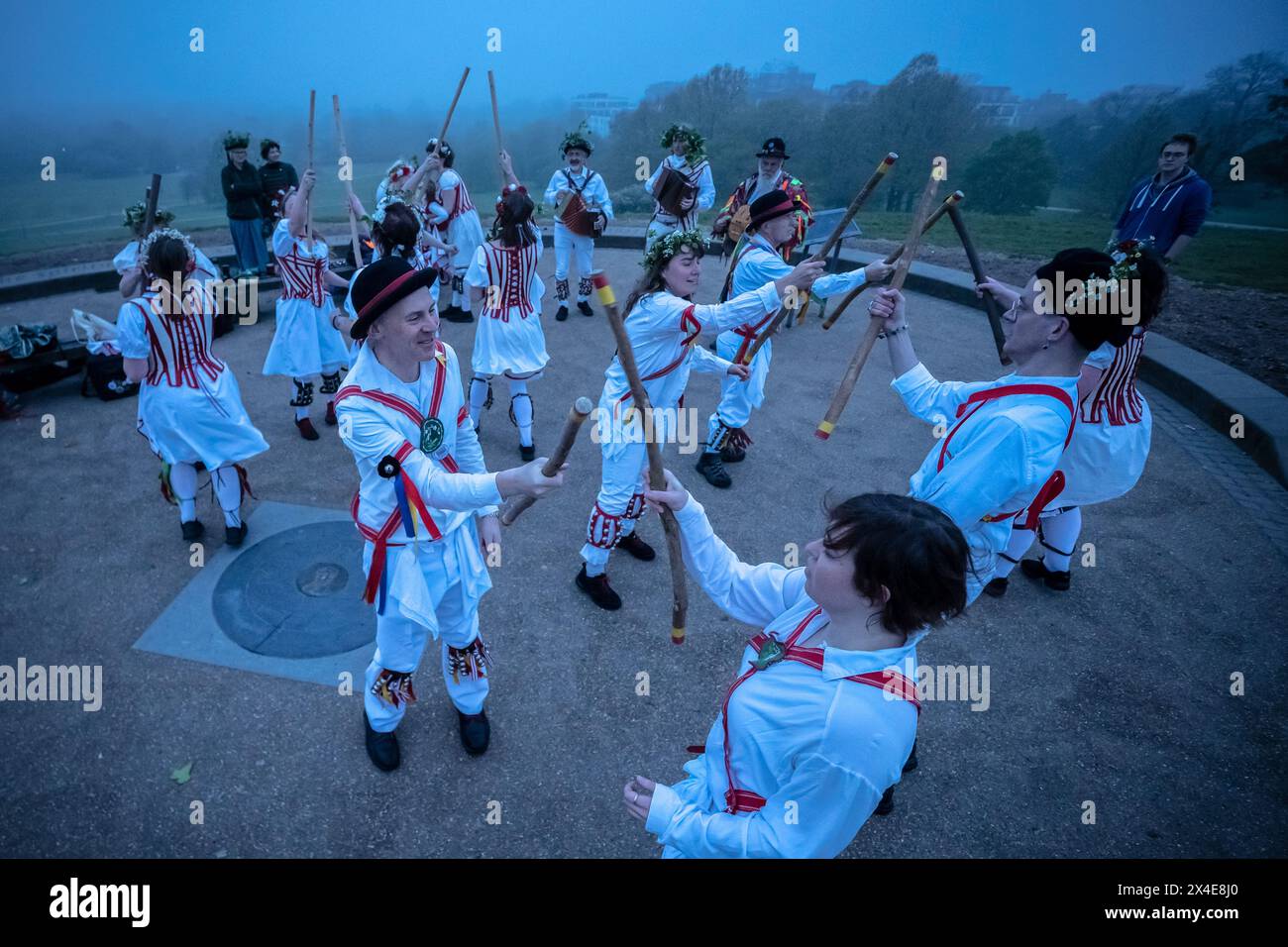 Le Belles of London City, gruppo femminile di Morris, si esibiscono in una danza del giorno di maggio durante un'alba nebbiosa a Primrose Hill, Londra, Regno Unito Foto Stock