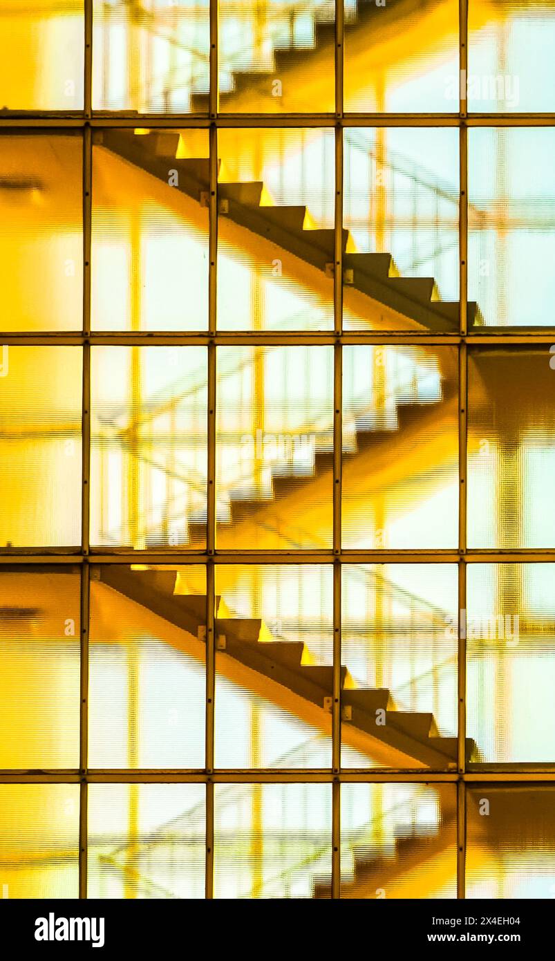 Moderna facciata in vetro con scala illuminata visibile attraverso le finestre nel quartiere Hansaviertel, Berlino, Germania, che mostra l'architettura degli anni '50. Foto Stock