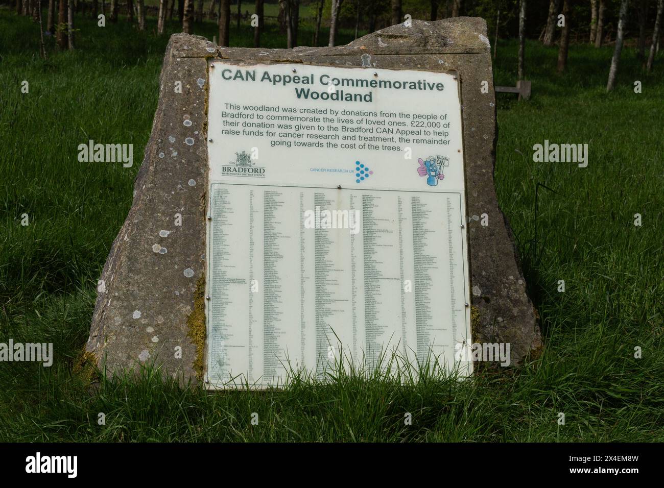 Una targa di pietra in un Memorial Wood a St Ives Estate, Bingley. I nomi di coloro che hanno fatto piantare un albero in loro memoria sono elencati sulla targa. Foto Stock