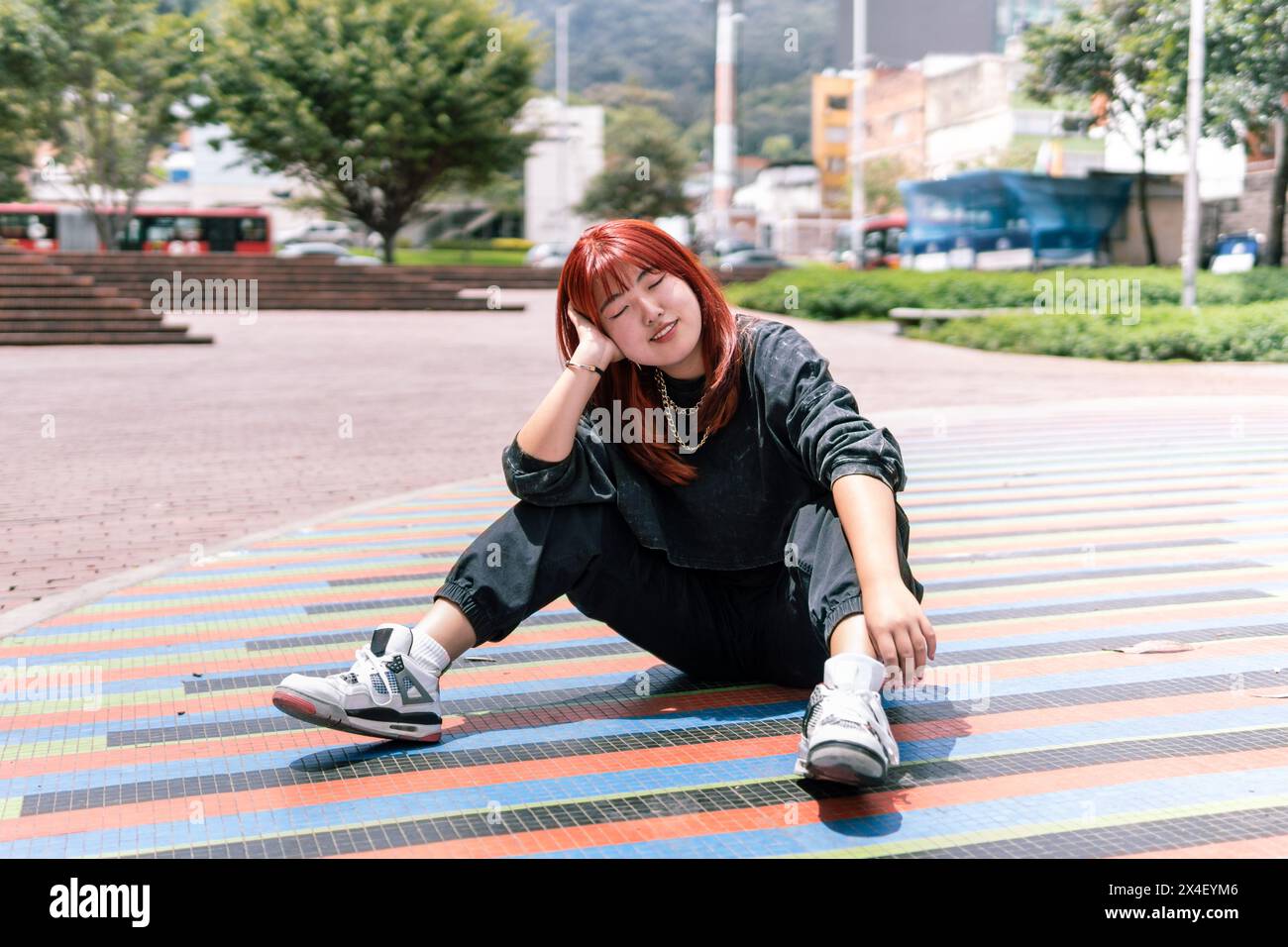 La donna coreana gode di un momento di relax seduto su un colorato mosaico urbano Foto Stock