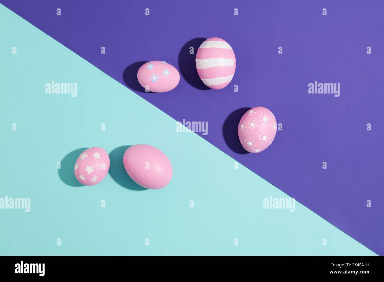 Su sfondo blu scuro e chiaro, uova rosa dipinte a mano. Fotografato dall'alto. Scena minimalista con uova per la pubblicità sulla celebrità di Pasqua Foto Stock