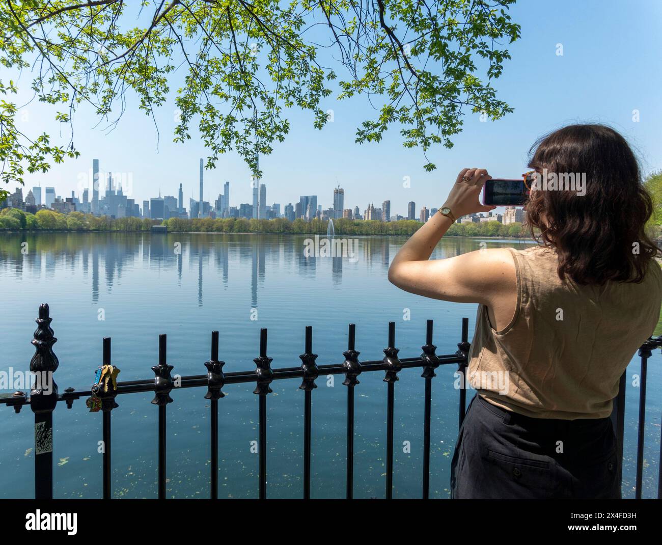 Donna che fotografa il bacino idrico di Central Park, New York City, Stati Uniti Foto Stock
