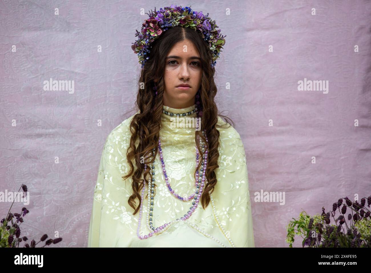 Colmenar Viejo, Spagna. 2 maggio 2024. Antia, 15 anni, vestita da Maya, rimane seduta su un altare, durante la celebrazione di "la Maya", nella città di Madrid di Colmenar Viejo. "La Maya" sono ragazze tra i 7 e i 14 anni che siedono per due ore in un altare decorato con fiori e piante per celebrare l'inizio della primavera. Questa tradizione originaria della città di Colmenar Viejo, Madrid, risale al medioevo, secondo antichi documenti. Credito: SOPA Images Limited/Alamy Live News Foto Stock