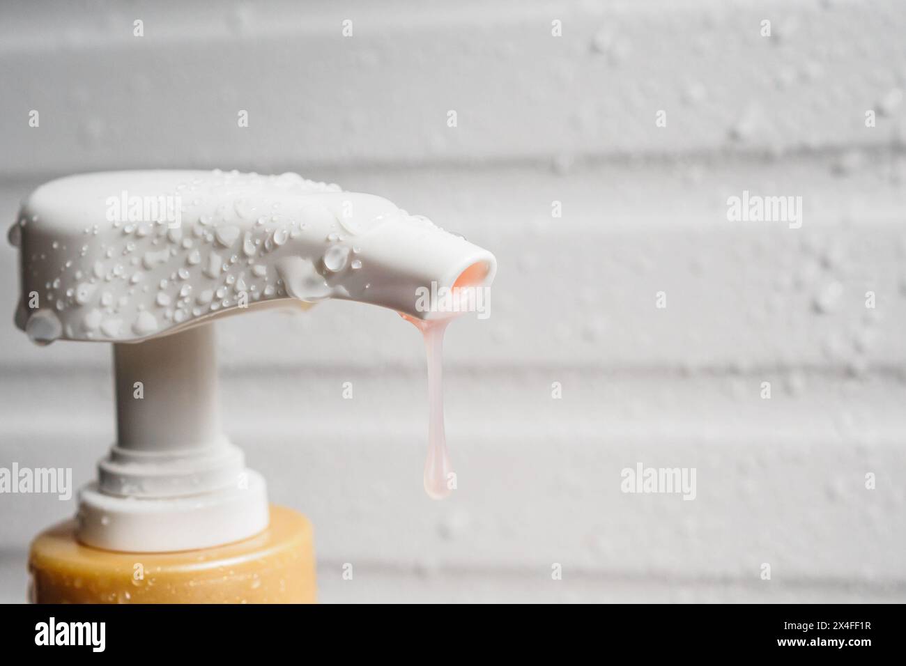 Goccia d'acqua sulla pompa erogatrice di sapone liquido durante il bagno Foto Stock