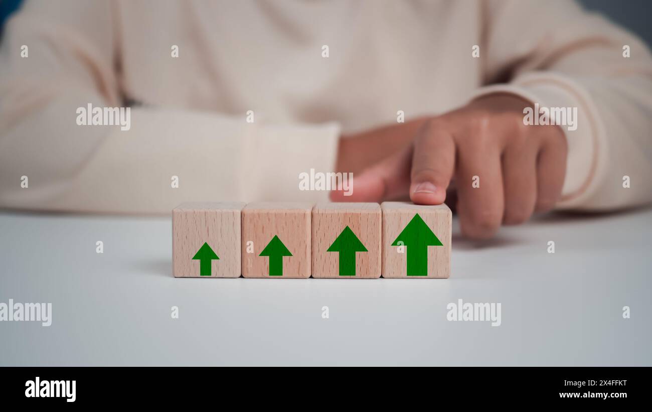 L'uomo d'affari tocca il suo blocco di legno con una freccia verde per il futuro piano di crescita della sua organizzazione. finanza, gestione, piano, mana Foto Stock