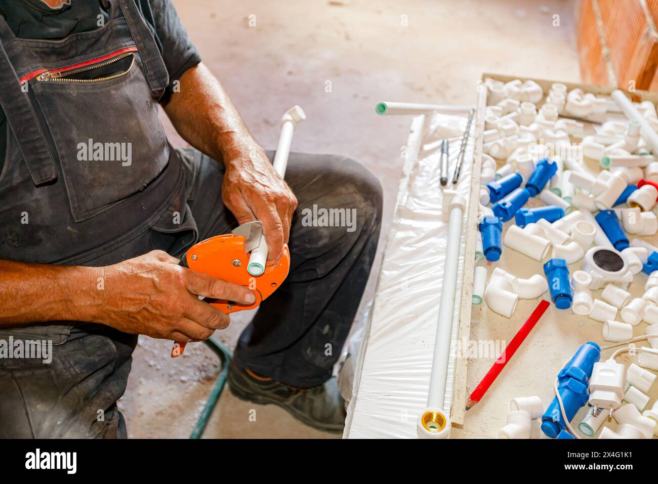 Le mani dell'idraulico preparano tubi in polipropilene per collegarli in tubazioni, officine in cantieri edili interni, edifici residenziali. Foto Stock