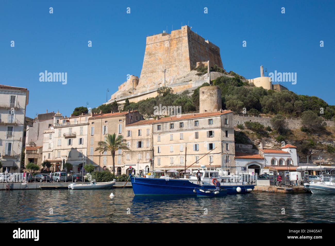 Bonifacio, Corse-du-Sud, Corsica, Francia. Vista sul porto fino alla cittadella, il Bastion de l'Etendard che torreggia sopra gli edifici della banchina. Foto Stock
