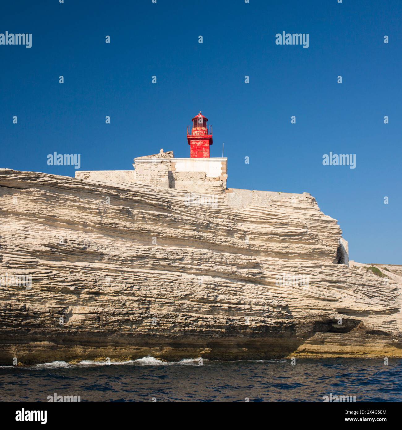 Bonifacio, Corse-du-Sud, Corsica, Francia. Vista dal mare sul Phare de la Madonetta, l'iconico faro sulla scogliera della città. Foto Stock