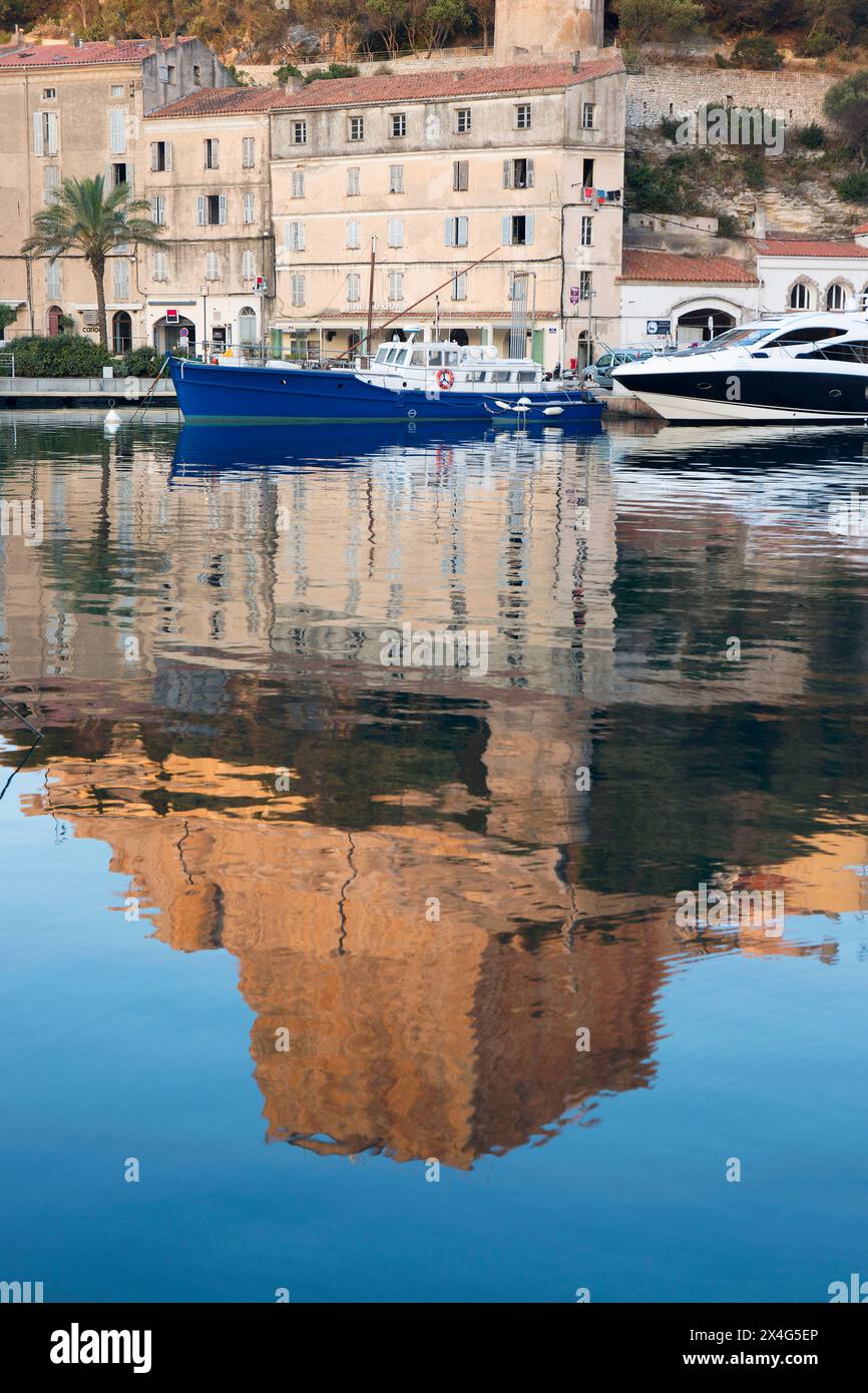 Bonifacio, Corse-du-Sud, Corsica, Francia. Vista sul porto all'alba, il Bastion de l'Etendard si riflette nell'acqua ferma. Foto Stock