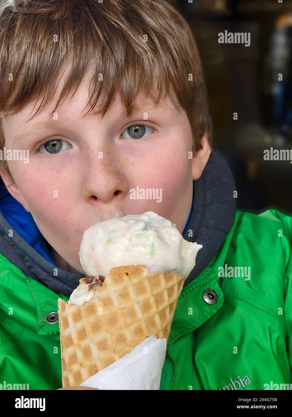 Il ragazzo con gli occhi luminosi si diverte con un delizioso cono gelato Foto Stock