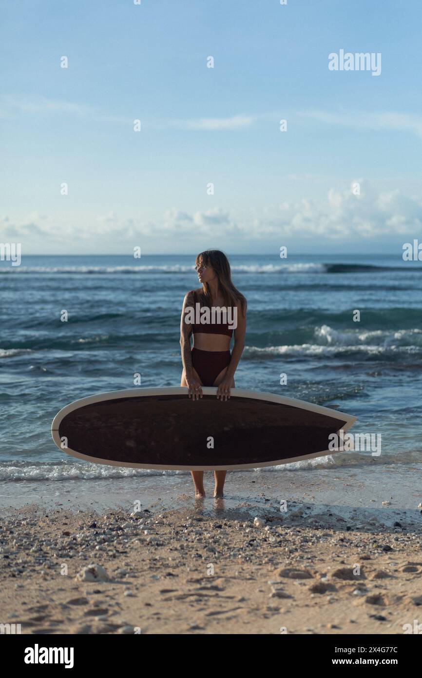 Giovane donna con tavola da surf su una spiaggia. Foto Stock
