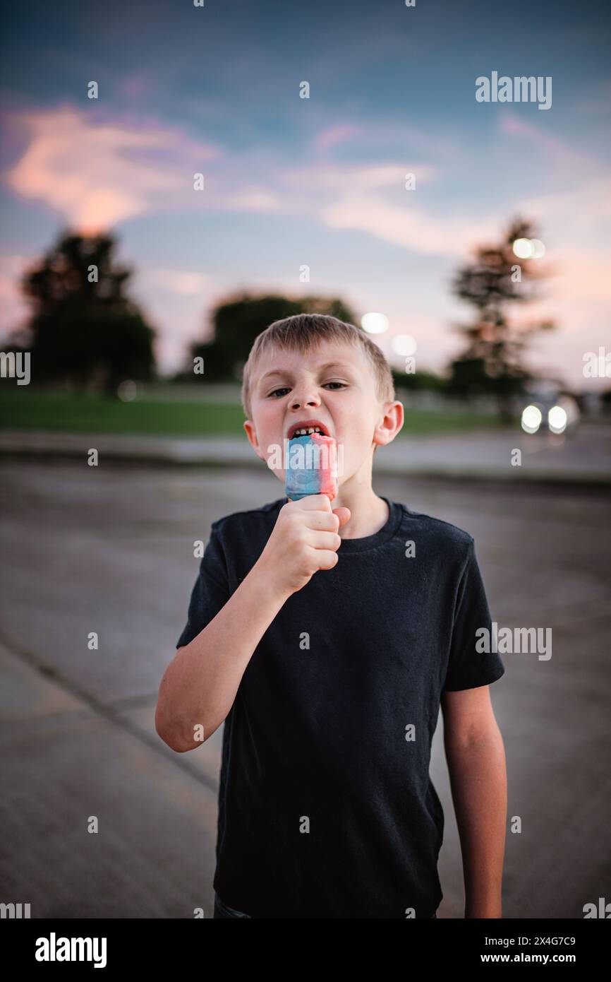 Il bambino si diverte con un fresco popsicle durante il tramonto estivo Foto Stock