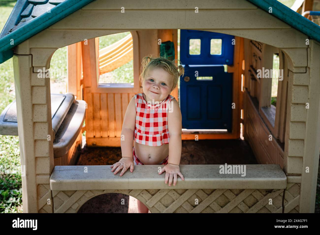 I bimbi piccoli si preparano alla finestra del playhouse all'aperto Foto Stock