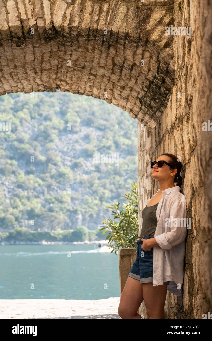 Donna appoggiata contro un muro medievale di pietra Foto Stock