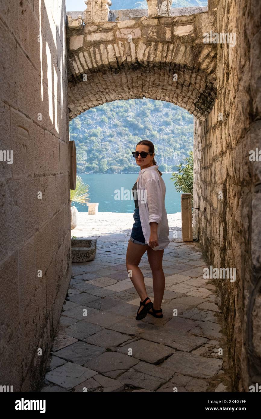 Donna che cammina attraverso vecchie mura di pietra nella baia di Kotor Foto Stock