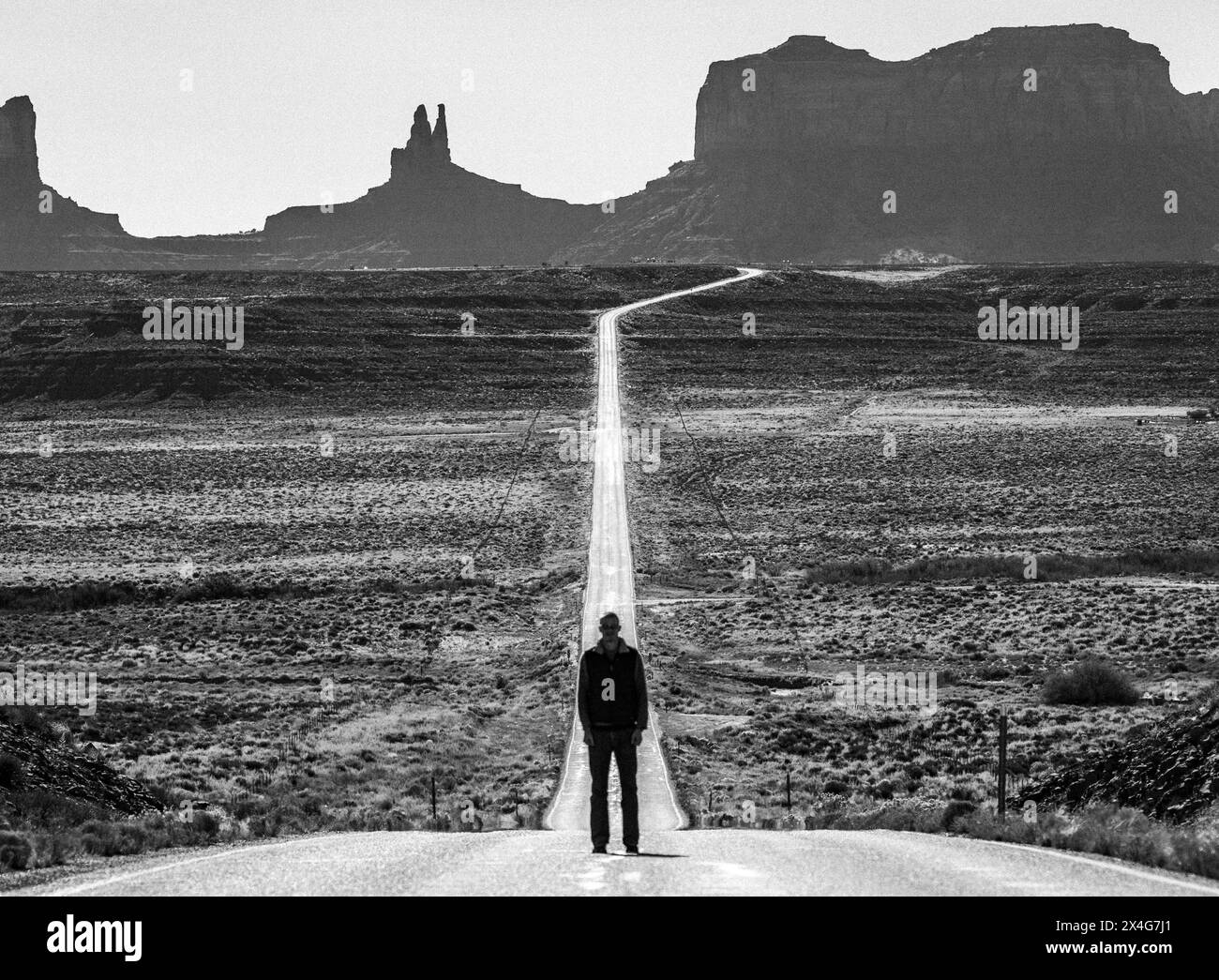 L'uomo si trova da solo al centro della strada, Monument Valley, Utah Foto Stock