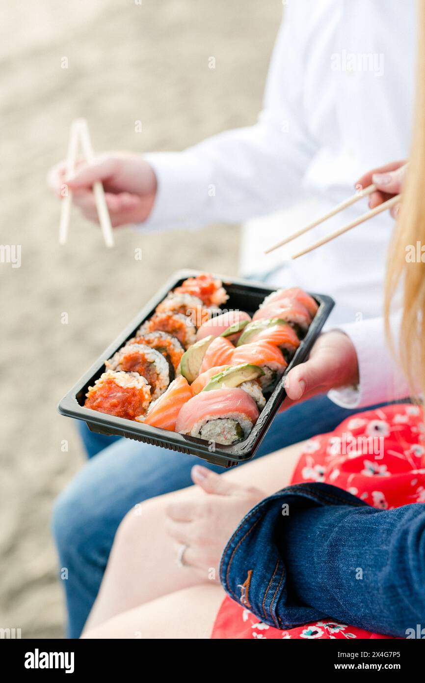 Gustate sushi fresco con bacchette in una giornata di spiaggia Foto Stock