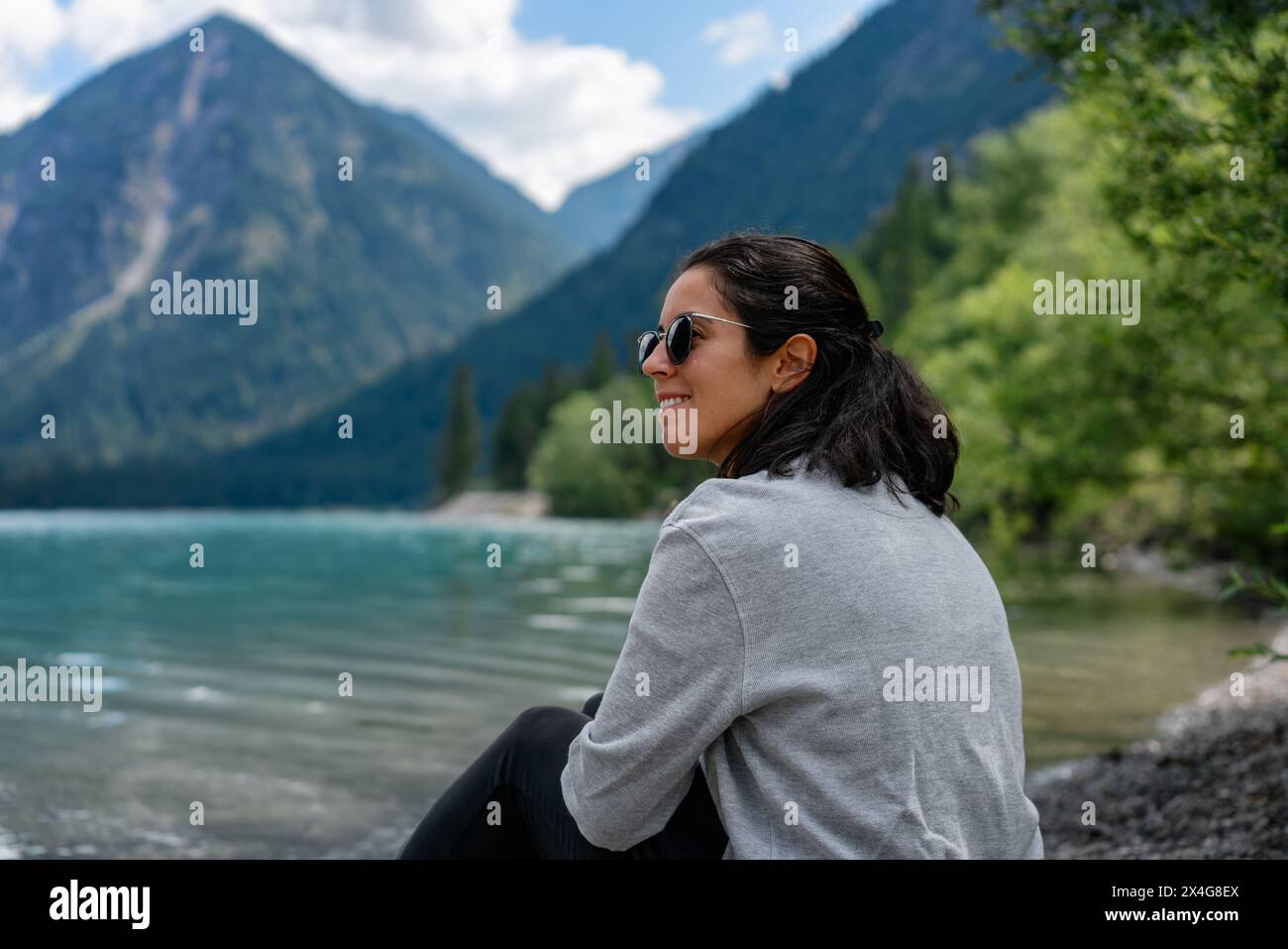 Donna che guarda sul lato con un lago e montagne sullo sfondo Foto Stock