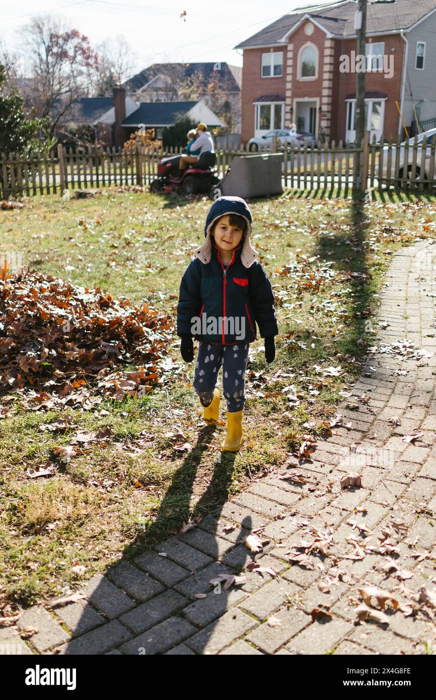 Giovane ragazzo asiatico bambino di fronte a casa nel quartiere in autunno Foto Stock