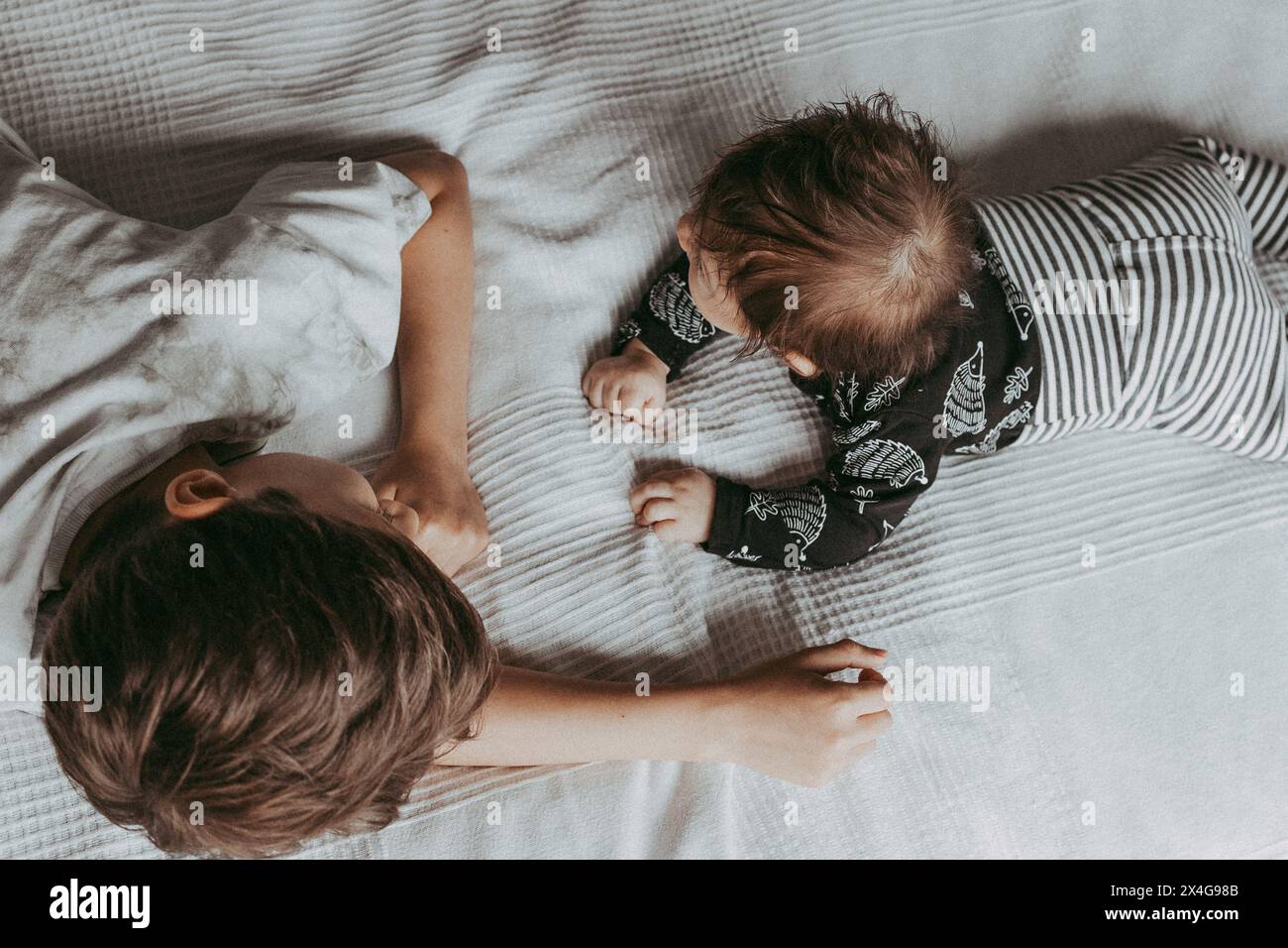 I fratelli sdraiavano sul letto in camera da letto e si guardavano a vicenda Foto Stock