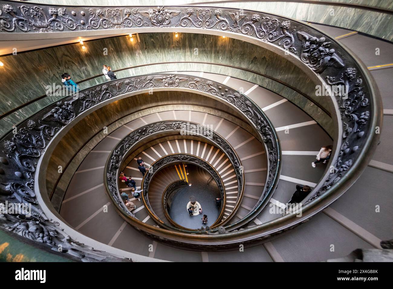 Scala a chiocciola con ringhiere in metallo ornate nei Musei Vaticani, vista dall'alto con le persone che scendono. Scala elicoidale Bramante Foto Stock