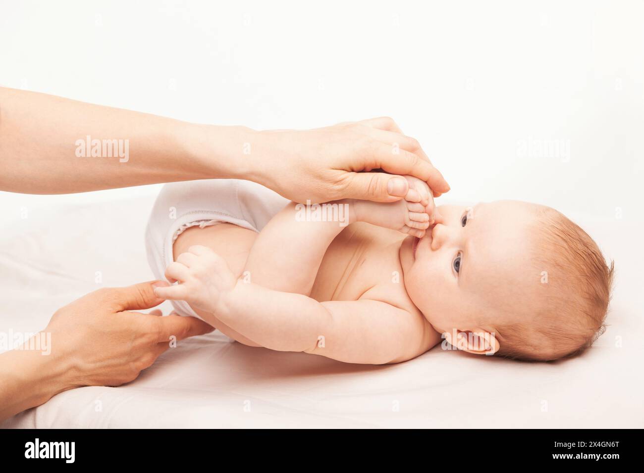 Fisioterapista che svolge attività di sviluppo infantile manipolando le gambe del bambino per aumentare la flessibilità di caviglie anche e ginocchia Foto Stock