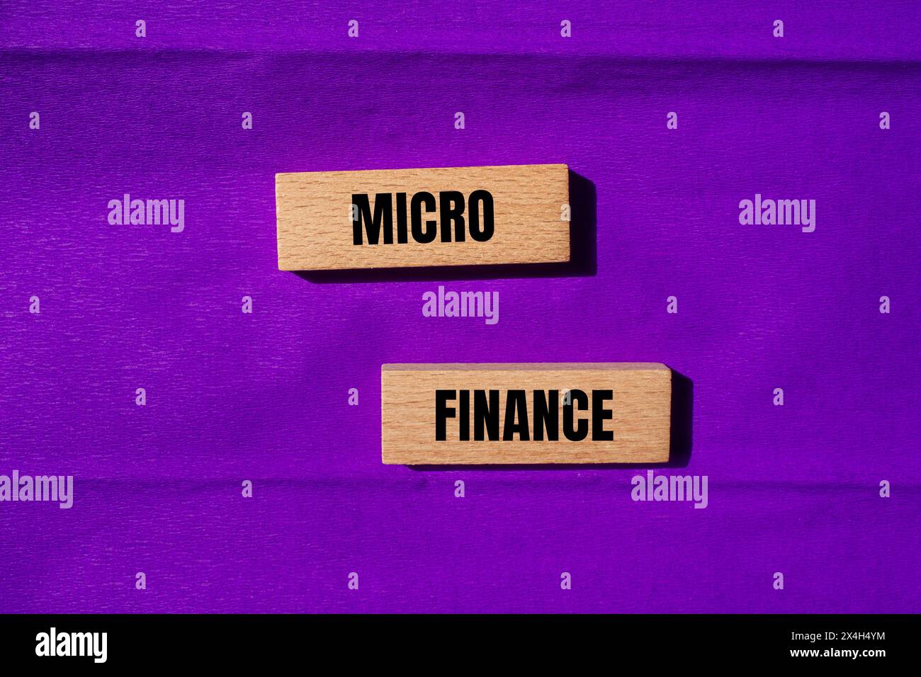 Parole di microfinanza scritte su blocchi di legno con sfondo viola. Simbolo concettuale del business della microfinanza. Copia spazio. Foto Stock