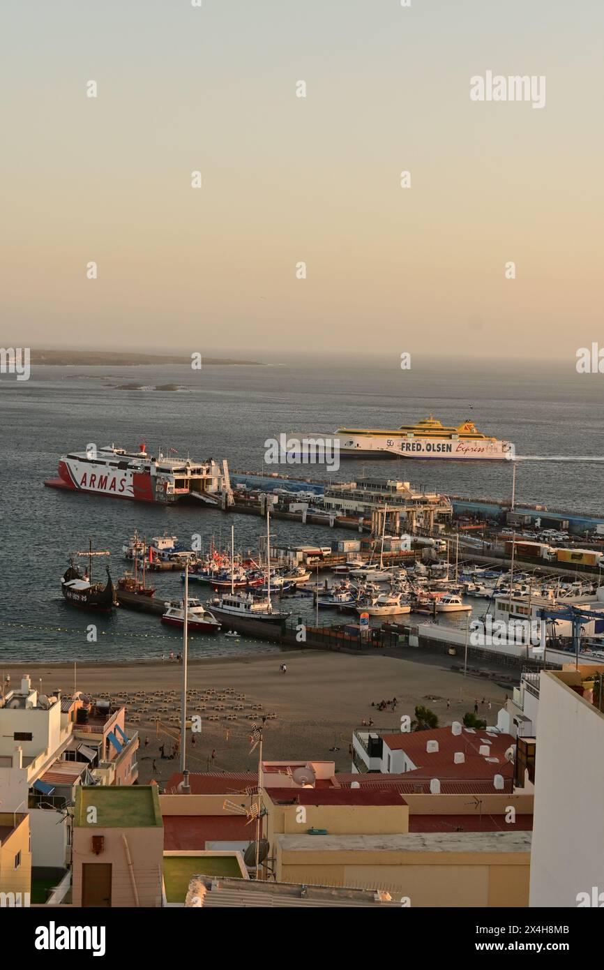 vista di un porto affollato con traghetti e barche attraccate, sotto un cielo limpido durante il tramonto, che riflette la calma ma attiva atmosfera marittima Foto Stock