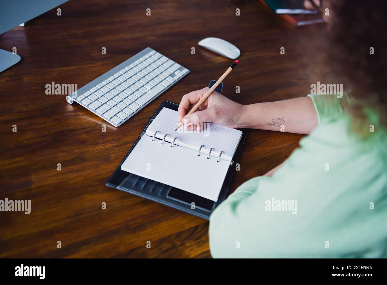 Foto di una donna di successo seduta in un ufficio moderno scrivendo appunti sulla postazione di lavoro a piano settimanale Foto Stock