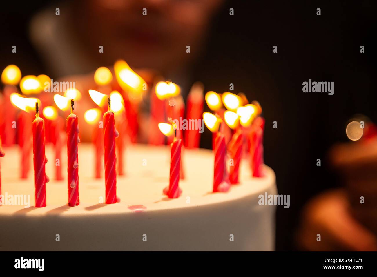Goiania, Goias, Brasile – 27 aprile 2024: Dettaglio di diverse candele su una torta di compleanno con il volto sfocato sullo sfondo. Foto Stock