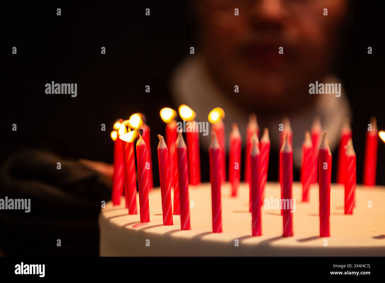 Goiania, Goias, Brasile – 27 aprile 2024: Dettaglio di diverse candele su una torta di compleanno con il volto sfocato sullo sfondo. Foto Stock