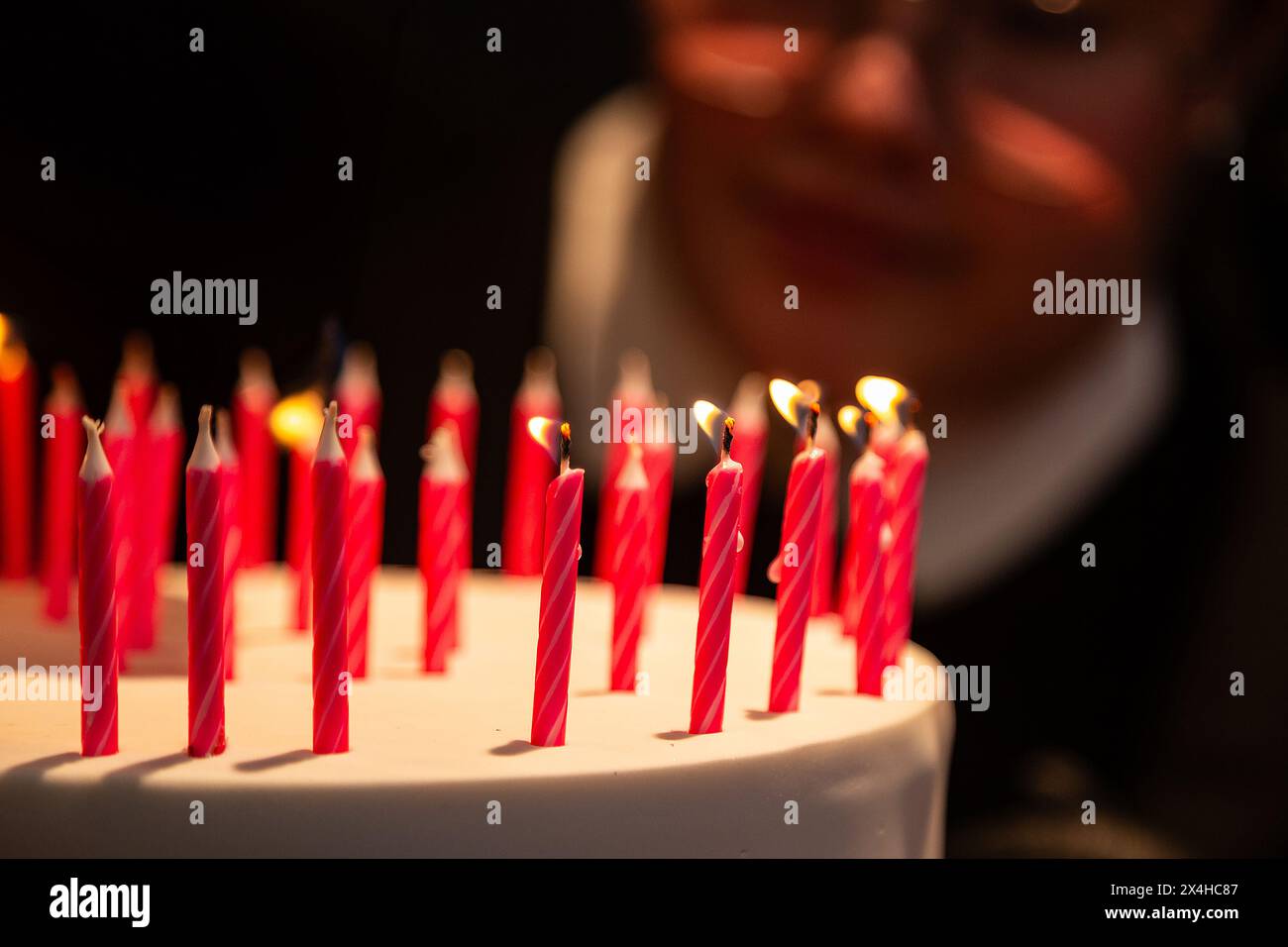 Goiania, Goias, Brasile – 27 aprile 2024: Dettaglio di diverse candele su una torta di compleanno con il volto sfocato sullo sfondo. Foto Stock