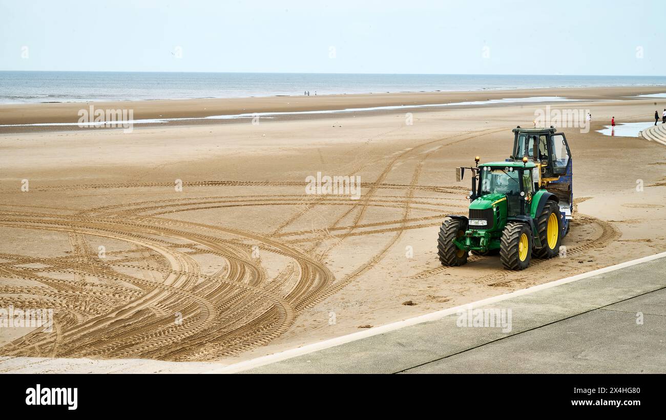 Trattore che trasporta il macchinario per la terra su un rimorchio sulla spiaggia di Blackpool Foto Stock