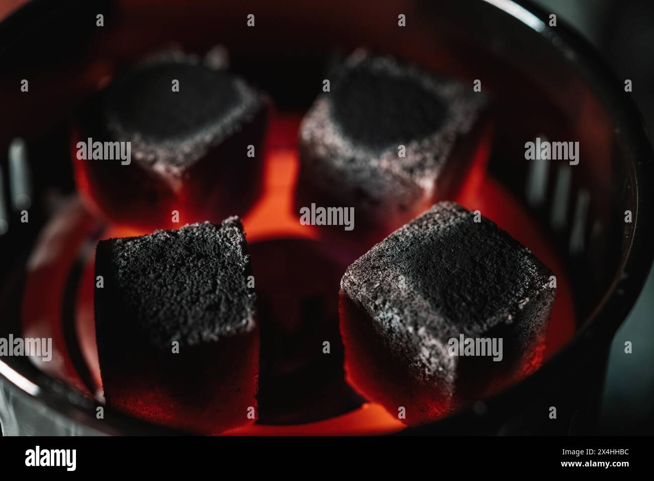 Primo piano di bricchette di carbone incandescenti in un riscaldatore elettrico, utilizzato specificamente per riscaldare i carboni shisha Foto Stock