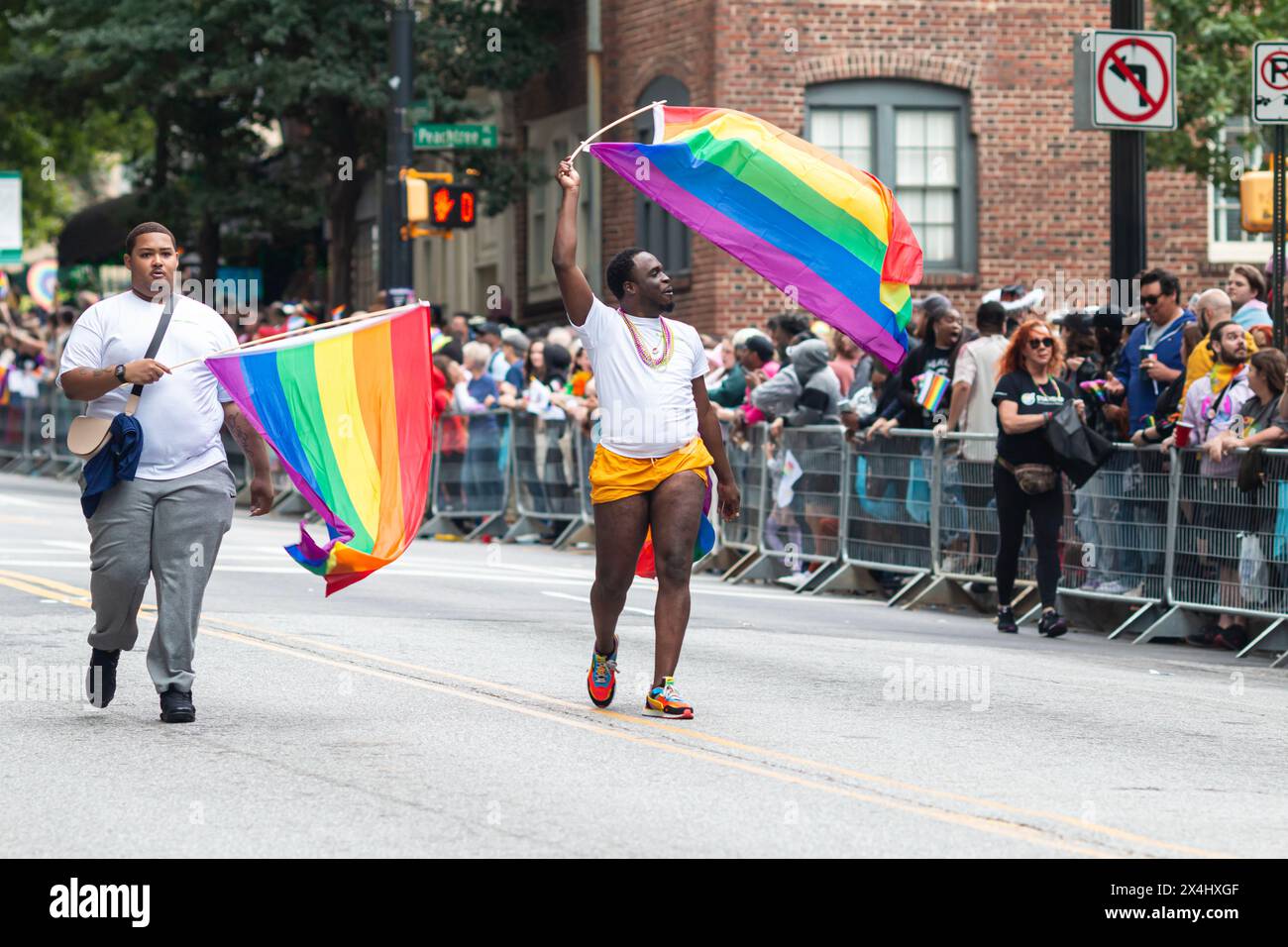 Atlanta, GA / USA - 15 ottobre 2023: Due uomini ondeggiano bandiere d'orgoglio mentre camminano nella sfilata annuale dell'orgoglio il 15 ottobre 2023 ad Atlanta, Georgia. Foto Stock