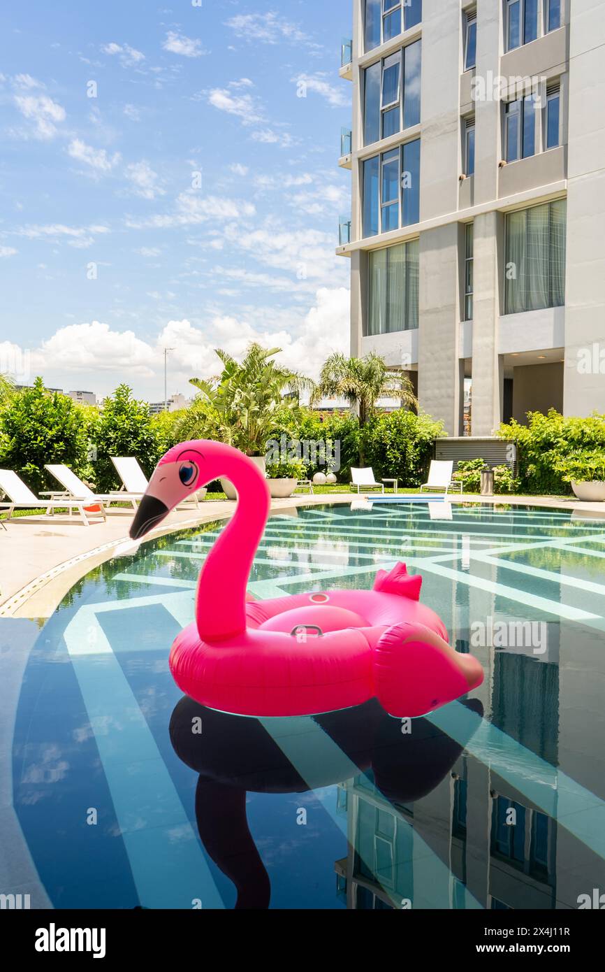 Un galleggiante rosa della piscina flamingo galleggia in una piscina. Scatto verticale Foto Stock