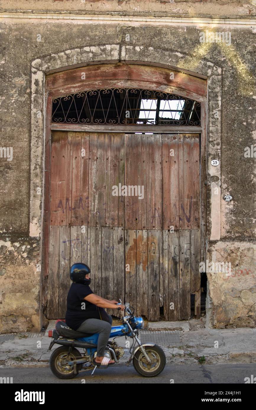 Donna grassa su un ciclomotore di fronte a un vecchio magazzino, scena rurale a Victoria, Duck, Argentina Foto Stock