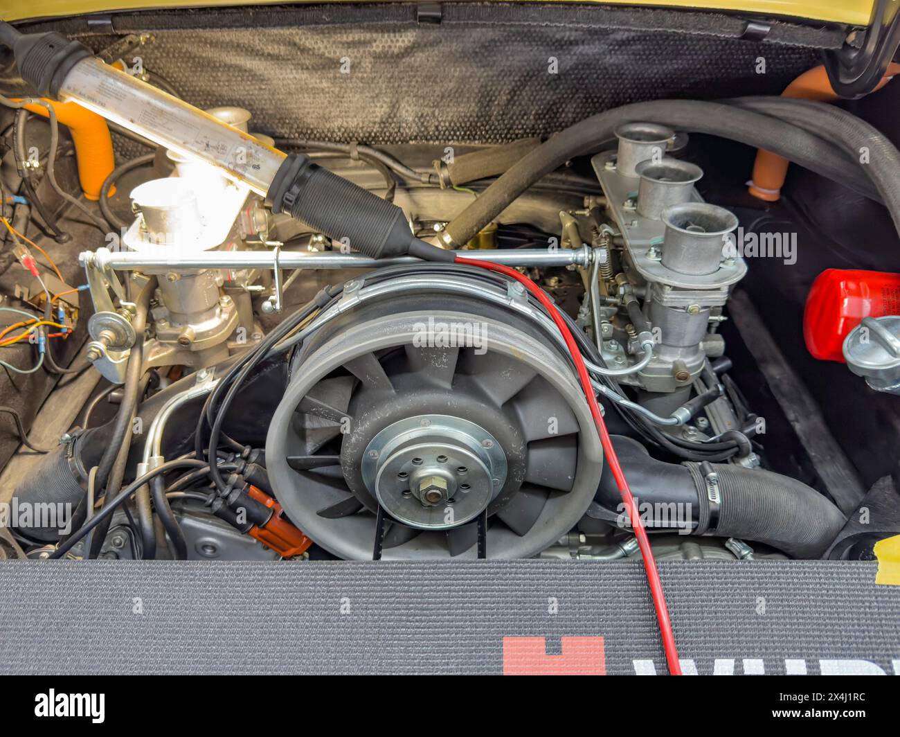 Vista nel vano motore della storica Porsche 911 d'epoca, ruota della ventola centrale anteriore, tre cilindri di destra del motore boxer, lato sinistro illuminato Foto Stock