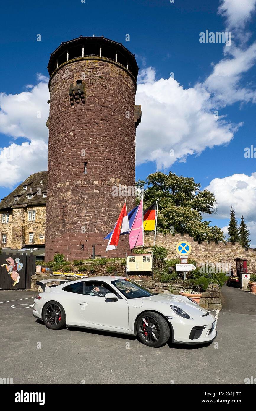 La Porsche 911 GT3 sorge di fronte al castello del XIII secolo oggi Burghotel Trendelburg con la torre del castello, Trendelburg, Weserbergland, Assia, Germania Foto Stock