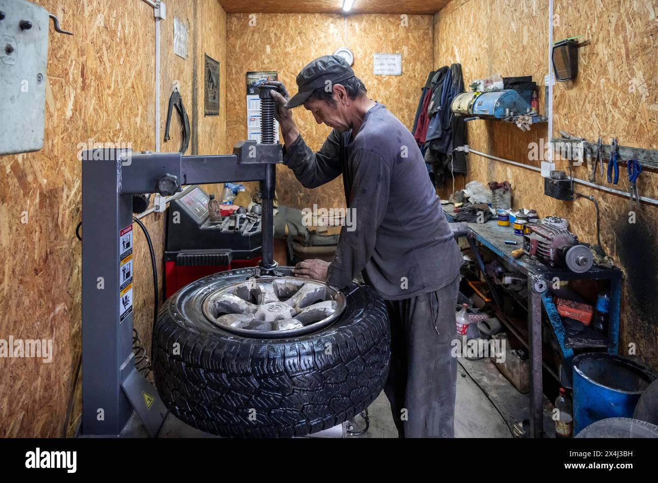 Officina, uomo che ripara un buco in una ruota di un'auto, Kirghizistan Foto Stock