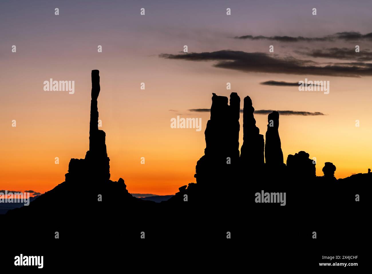 Alba dietro il famoso totem pole della Monument Valley e le vicine guglie, tutte formate da milioni di anni di erosione causata dal vento e dalla pioggia. Foto Stock